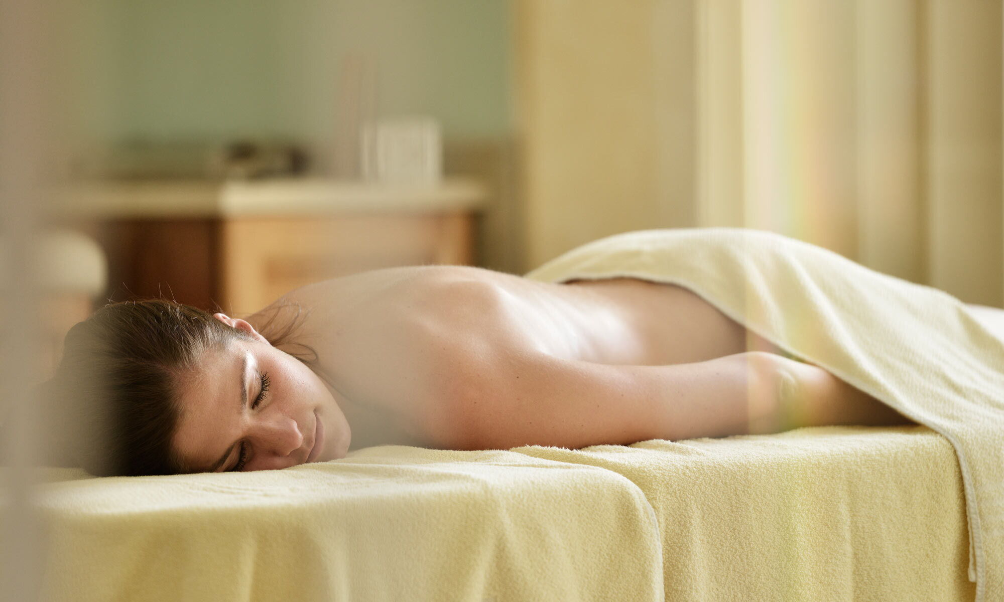 Woman relaxing on a massage table in the spa and wellness area of the Hotel Das-Schmidt on Lake Neusiedl