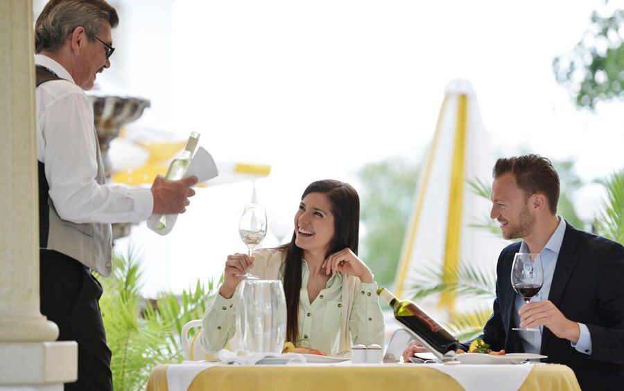 Ein Paar beim Abendessen, das von einem Sommelier über die verschiedenen Weinsorten beraten wird
