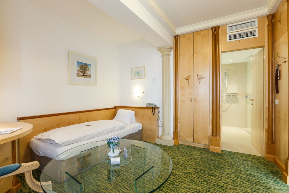 Das Vergissmeinnicht Zimmer mit einem Einzelbett und einem Glastisch im Privathotel Das-Schmidt