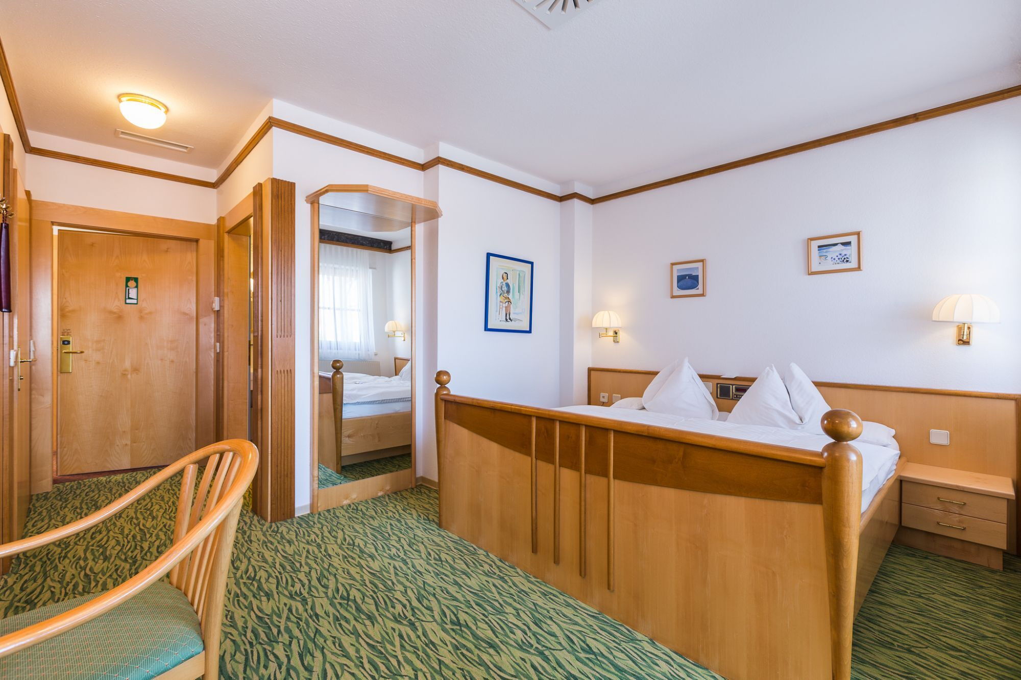 The well-equipped Storchennest room from the inside with bed, mirror, carpeted floor and lots of other furniture.