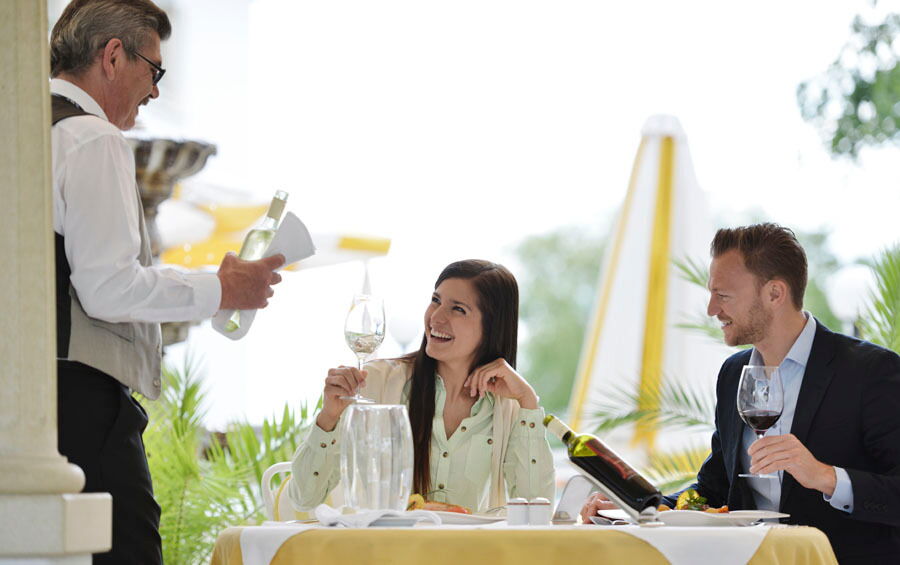Ein Paar beim Abendessen, das von einem Sommelier über die verschiedenen Weinsorten beraten wird