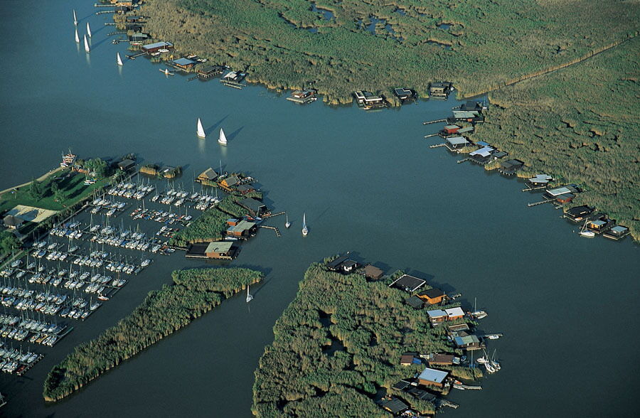 Luftaufnahme des Neusiedlersees mit Bootsanlegestellen und fahrenden Segelbooten