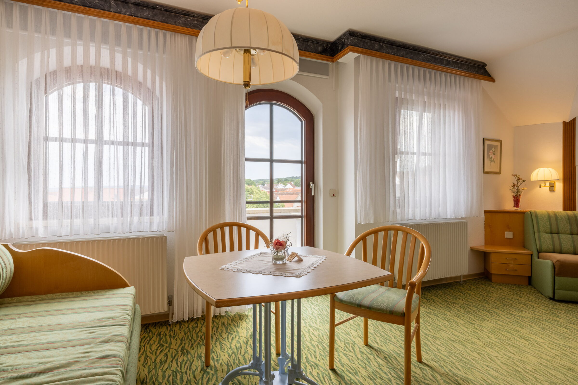 Ein ausgestattetes Zimmer mit Vorhängen, Tisch, Sesseln und vielen mehr Möbeln im Hotel Das Schmidt in Mörbisch; © Manfred Sodia Photography