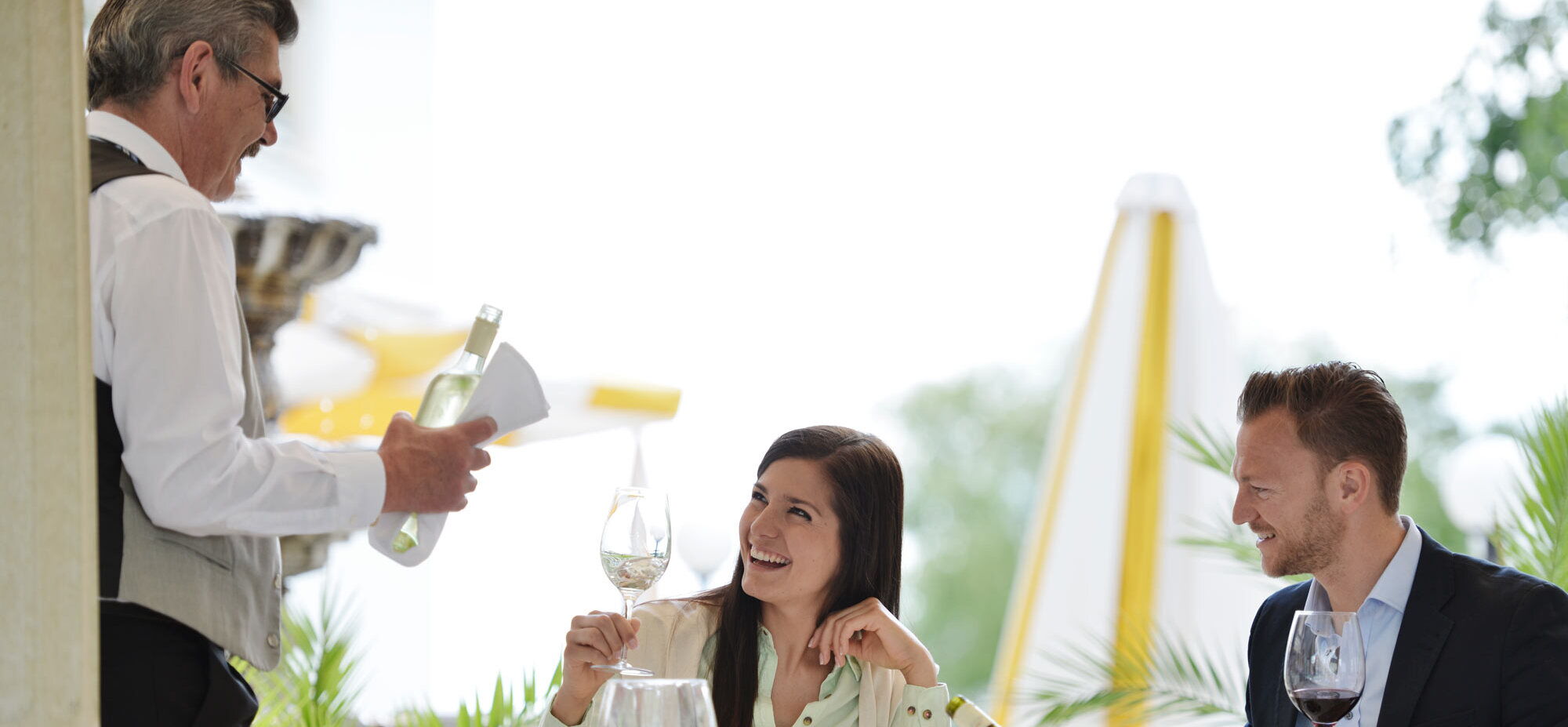 A couple eating dinner, advised by a sommelier about the different types of wine