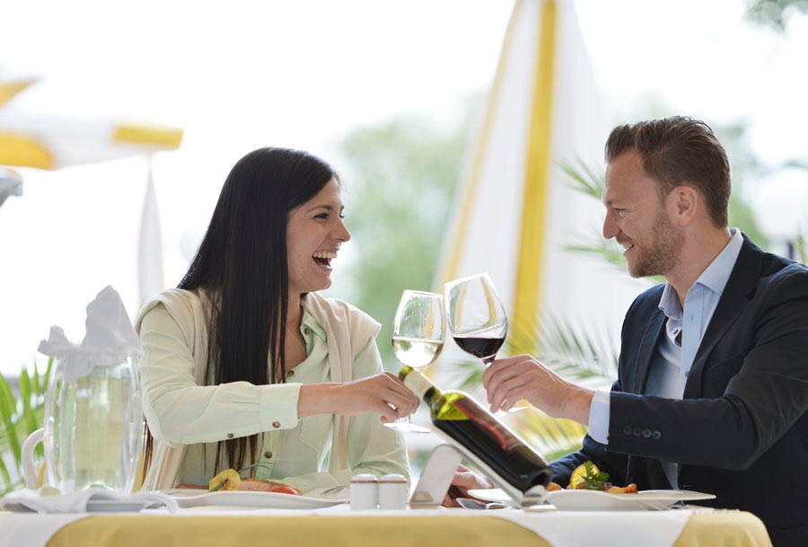 Zwei Personen die mit Weingläsern anstoßen und die Eigenbauweine genießen.