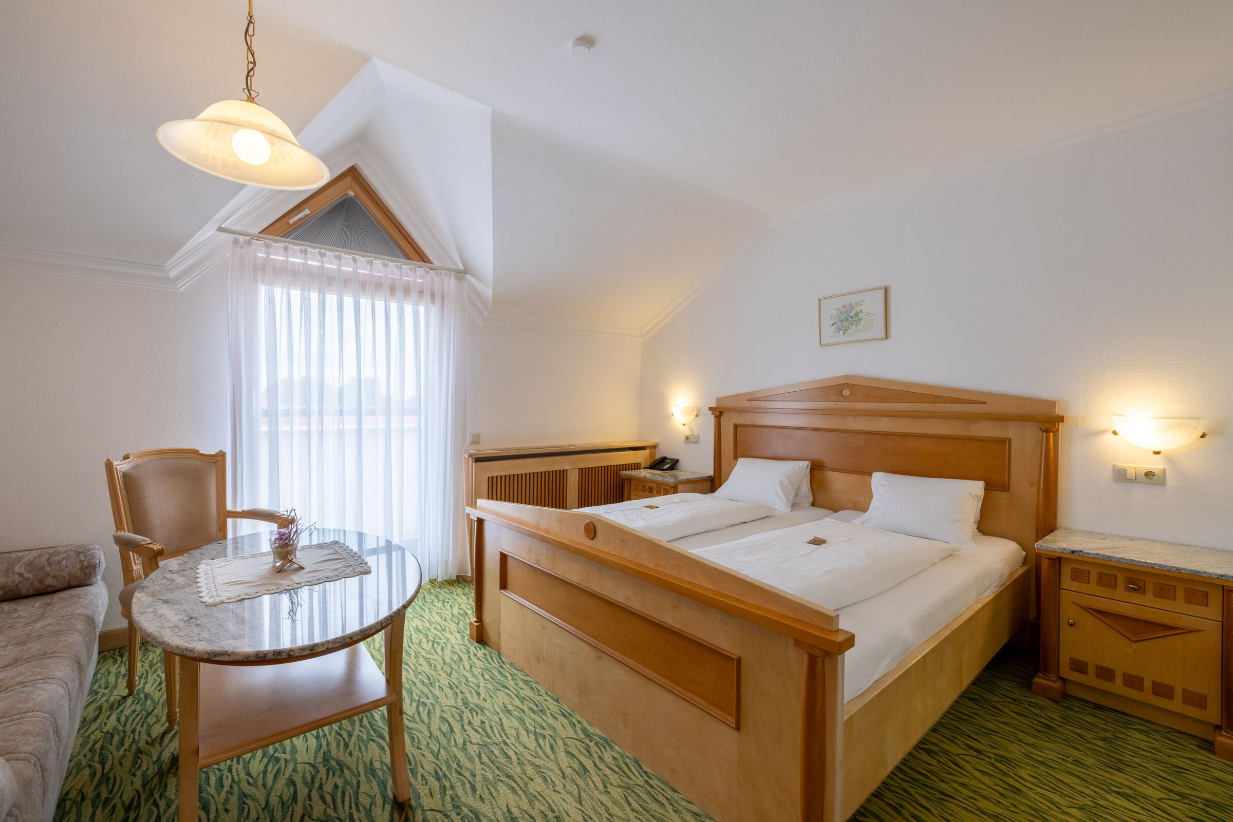 Das Flieder Zimmer mit einem Doppelbett, einer Couch und grünem Teppich im Privathotel Das-Schmidt; © Manfred Sodia Photography